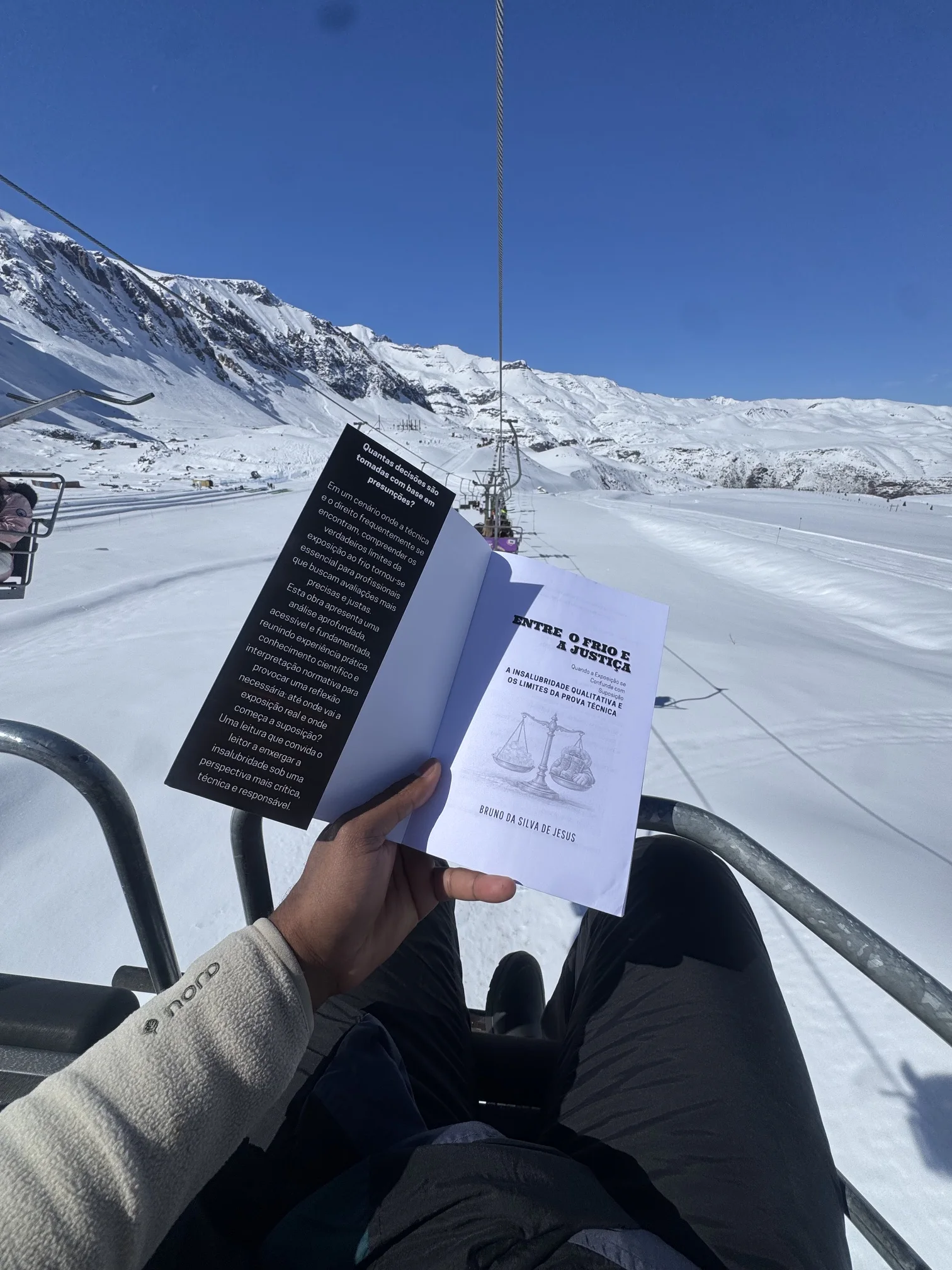 Livro Entre o Frio e a Justiça aberto em uma paisagem de neve