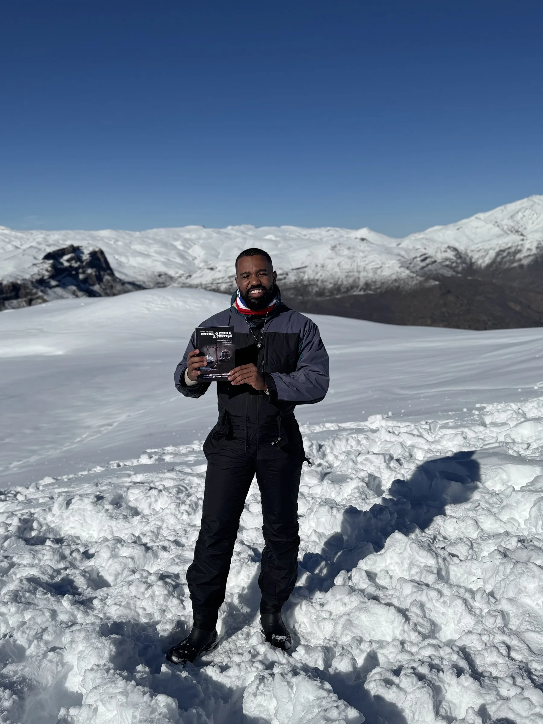 Bruno da Silva de Jesus segurando seu livro em uma paisagem nevada